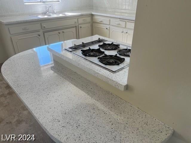 kitchen featuring white cabinetry, sink, white gas cooktop, and light stone countertops