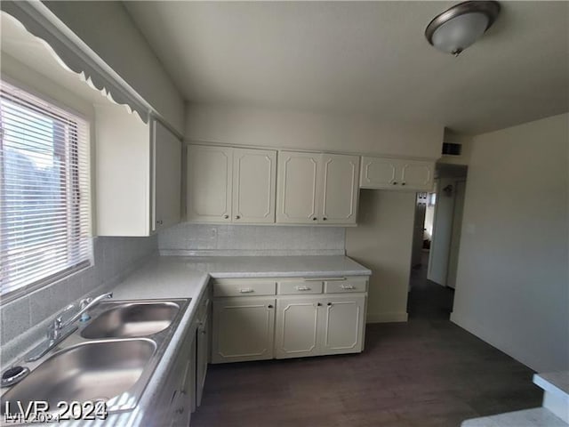 kitchen with a wealth of natural light, white cabinetry, dark hardwood / wood-style flooring, and sink