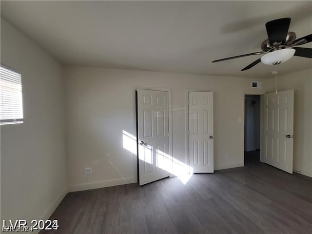 unfurnished bedroom with ceiling fan, two closets, and dark hardwood / wood-style floors