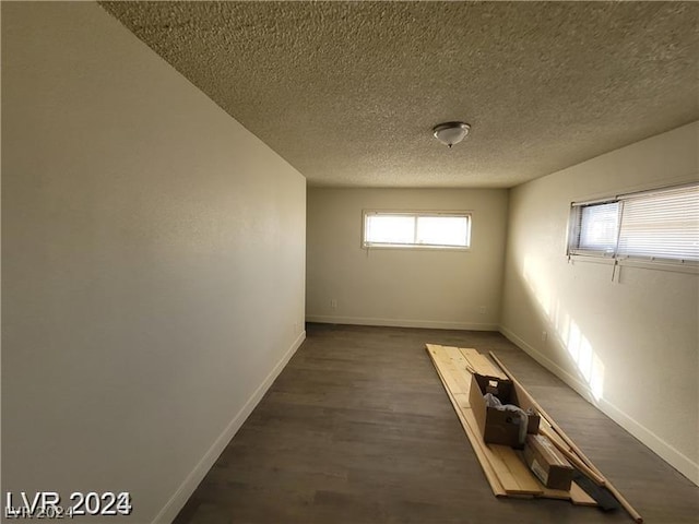 basement with dark hardwood / wood-style flooring, a wealth of natural light, and a textured ceiling