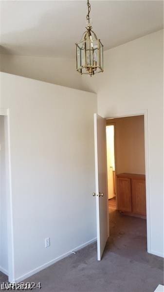 spare room featuring vaulted ceiling, a notable chandelier, and dark carpet