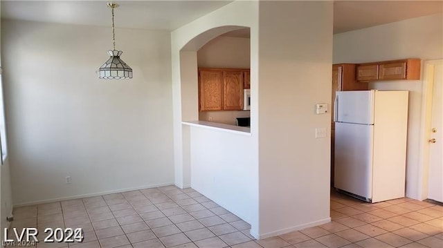 kitchen with white fridge, light tile patterned floors, and decorative light fixtures