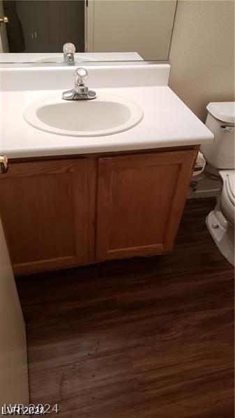 bathroom with hardwood / wood-style floors, toilet, and vanity