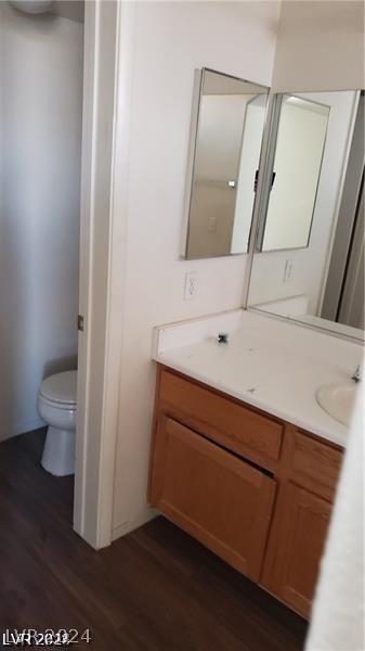 bathroom featuring toilet, wood-type flooring, and vanity