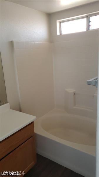 bathroom with vanity, hardwood / wood-style floors, and washtub / shower combination