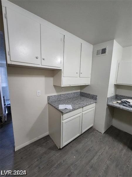 kitchen featuring built in desk, white cabinets, and dark wood-type flooring