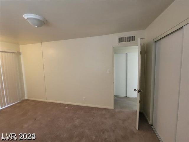 unfurnished bedroom featuring a closet and dark colored carpet