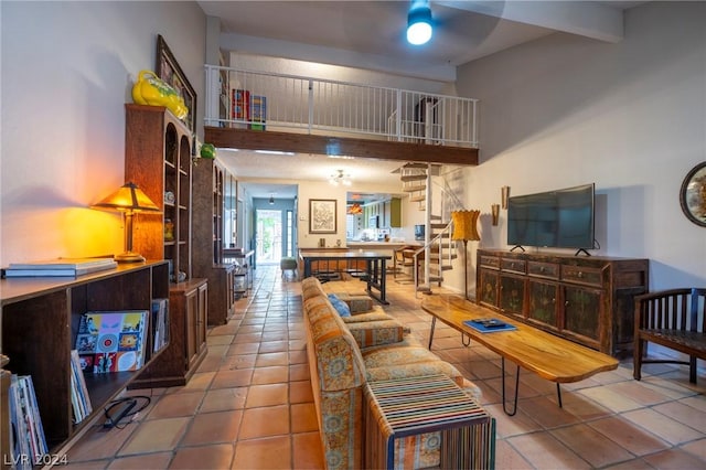 living area with stairs, beam ceiling, a towering ceiling, and tile patterned floors