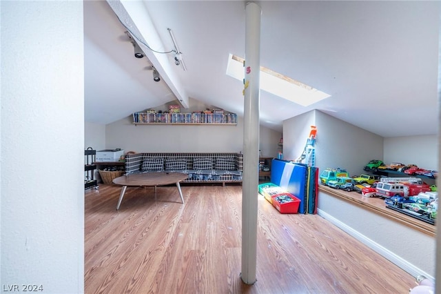 rec room with lofted ceiling with skylight, wood finished floors, and baseboards