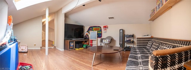 living room featuring baseboards, vaulted ceiling with skylight, visible vents, and wood finished floors