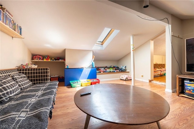 recreation room featuring lofted ceiling with skylight and wood finished floors