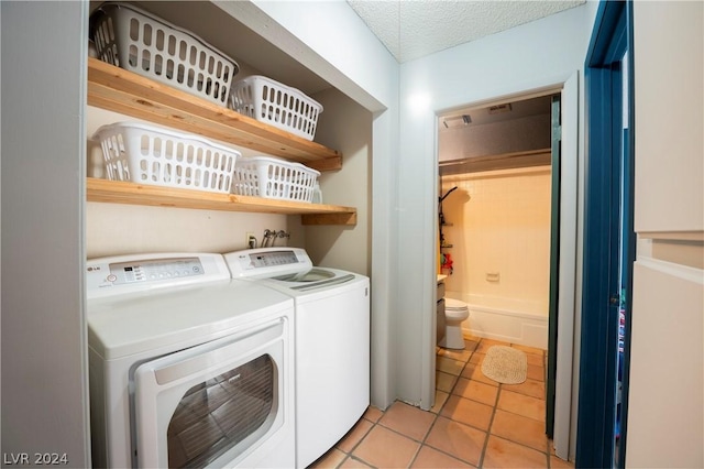 clothes washing area with a textured ceiling, laundry area, light tile patterned floors, and independent washer and dryer