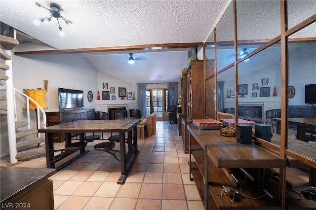 dining space featuring lofted ceiling, light tile patterned floors, stairs, and a glass covered fireplace