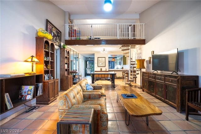 tiled living area with stairway and a towering ceiling