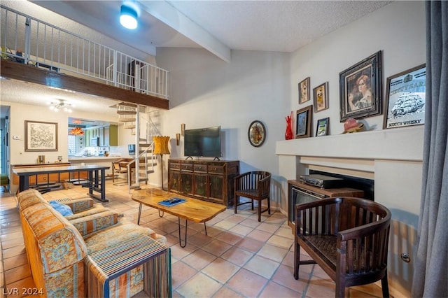 living area with a fireplace, lofted ceiling with beams, stairway, a textured ceiling, and tile patterned flooring