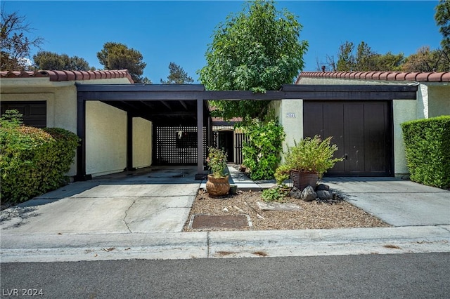 view of front of property featuring driveway, a tiled roof, a gate, a carport, and stucco siding