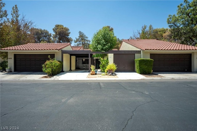 view of front facade with a garage, a tiled roof, driveway, and stucco siding