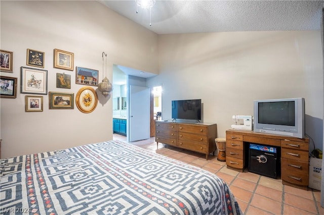 bedroom with light tile patterned floors, high vaulted ceiling, a textured ceiling, and ensuite bath