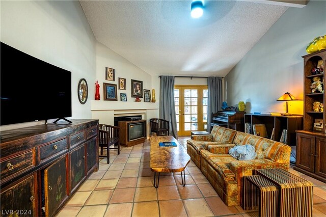 living room featuring light tile patterned floors, a glass covered fireplace, lofted ceiling, a textured ceiling, and french doors