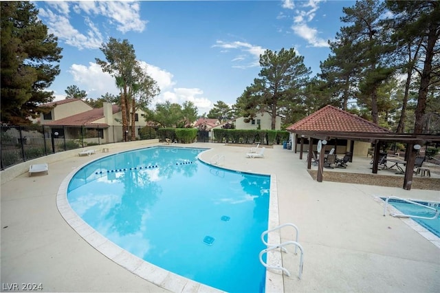 community pool with a patio, a gazebo, and fence