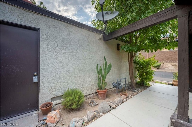 view of side of home with a patio area, fence, and stucco siding