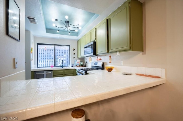 kitchen featuring tile countertops, visible vents, appliances with stainless steel finishes, a raised ceiling, and green cabinetry