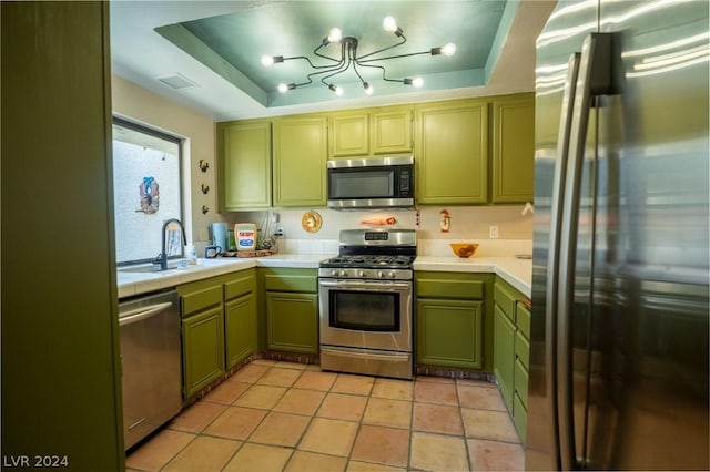 kitchen with tile countertops, green cabinets, stainless steel appliances, and a raised ceiling