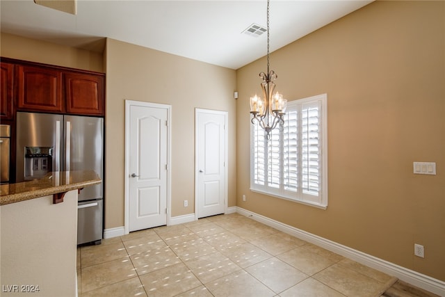 kitchen with light tile patterned floors, light stone countertops, a chandelier, stainless steel appliances, and decorative light fixtures