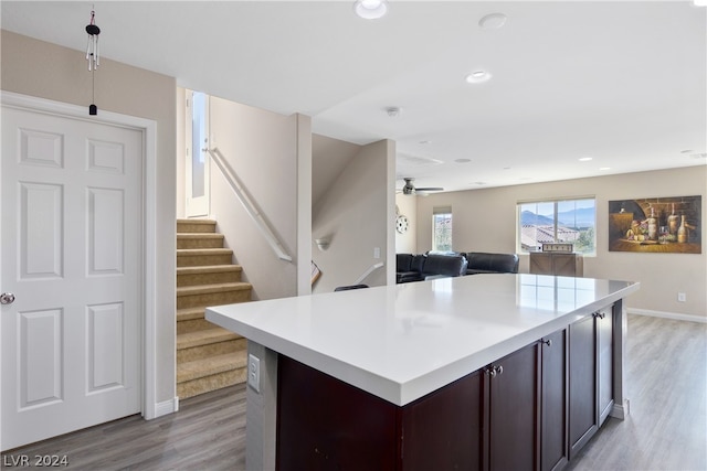 kitchen with a kitchen island, dark brown cabinets, ceiling fan, and light hardwood / wood-style floors