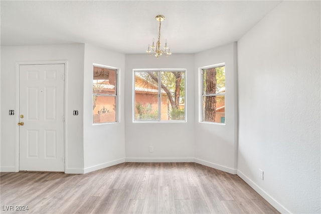 empty room featuring a chandelier and light hardwood / wood-style floors