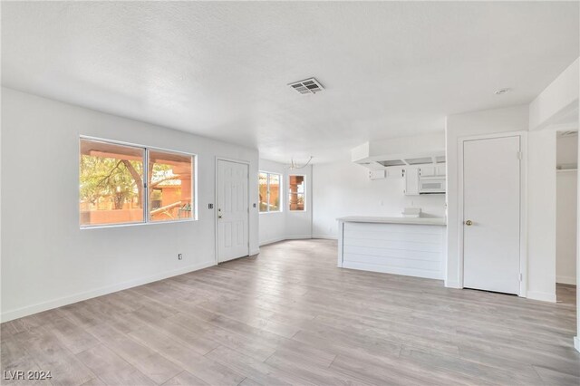 845 Mesquite Springs Dr Unit 102, Mesquite, NV 89027 - unfurnished living room featuring a chandelier, visible vents, light wood-style flooring, and baseboards