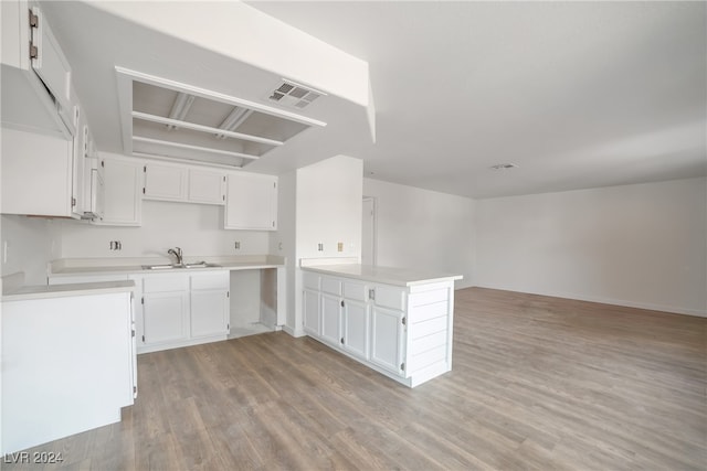 kitchen with sink, kitchen peninsula, light hardwood / wood-style floors, and white cabinetry