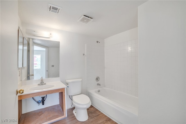 full bathroom featuring vanity, tiled shower / bath, hardwood / wood-style flooring, and toilet