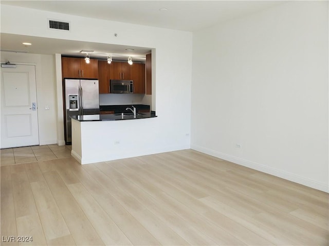 kitchen featuring sink, kitchen peninsula, stainless steel appliances, and light hardwood / wood-style flooring