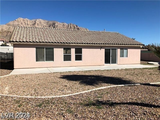 back of property with a mountain view and a patio