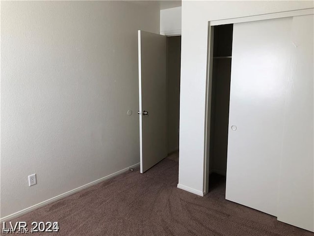 unfurnished bedroom with a closet and dark carpet