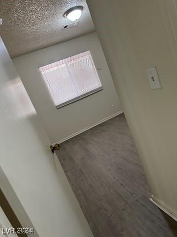 spare room featuring a textured ceiling and dark hardwood / wood-style flooring