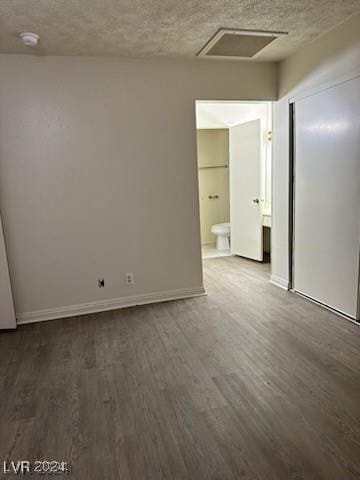 spare room with a textured ceiling and dark wood-type flooring