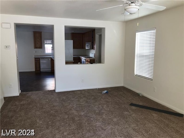 unfurnished living room with ceiling fan and dark colored carpet