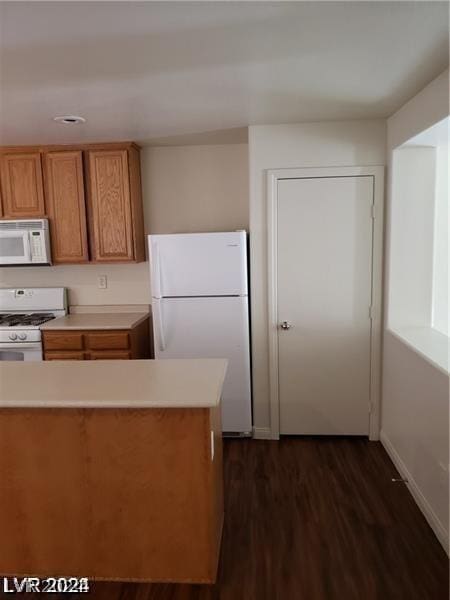 kitchen featuring white appliances and dark hardwood / wood-style flooring