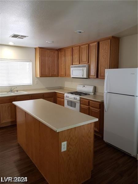 kitchen featuring dark wood-type flooring, sink, white appliances, and a center island