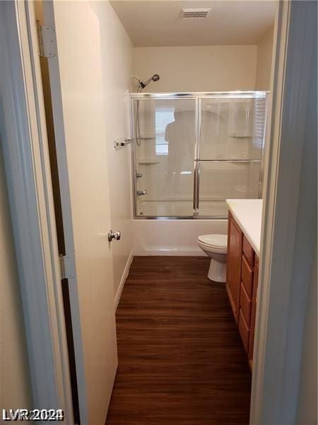 full bathroom featuring toilet, vanity, bath / shower combo with glass door, and hardwood / wood-style flooring