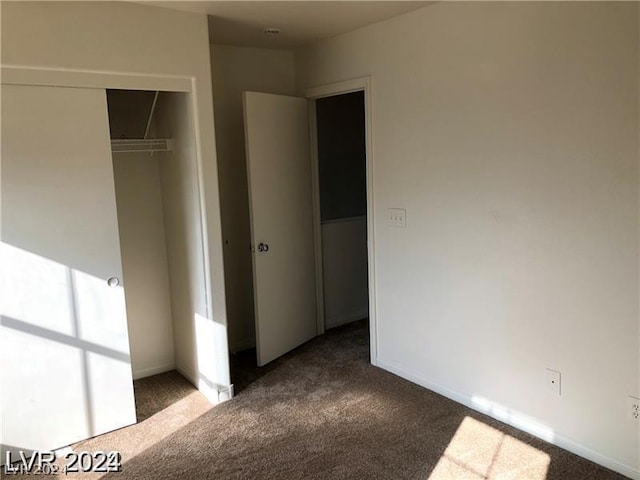 unfurnished bedroom featuring a closet and dark colored carpet