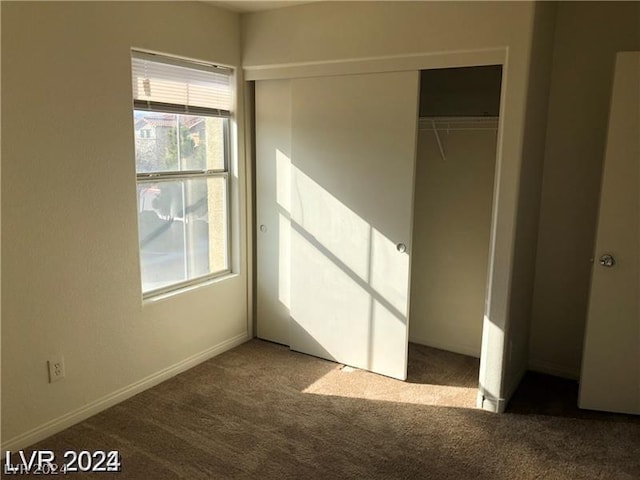 unfurnished bedroom featuring a closet and dark carpet