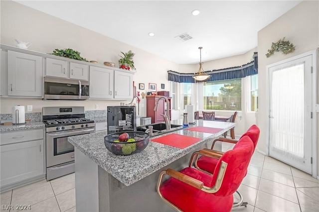 kitchen featuring stainless steel appliances, sink, a center island with sink, and a kitchen breakfast bar