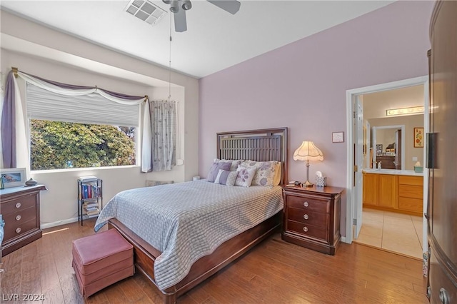 bedroom with hardwood / wood-style flooring, ensuite bathroom, and ceiling fan