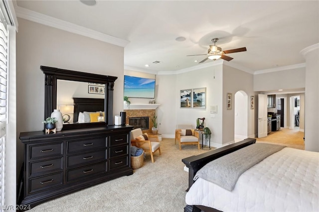 bedroom featuring a fireplace, ceiling fan, crown molding, and light carpet