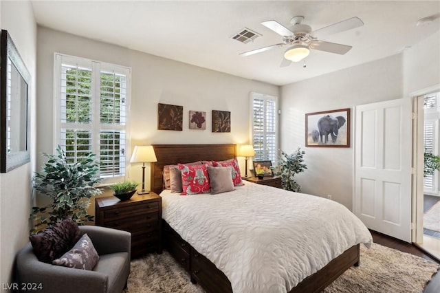 bedroom with multiple windows, ceiling fan, and hardwood / wood-style flooring