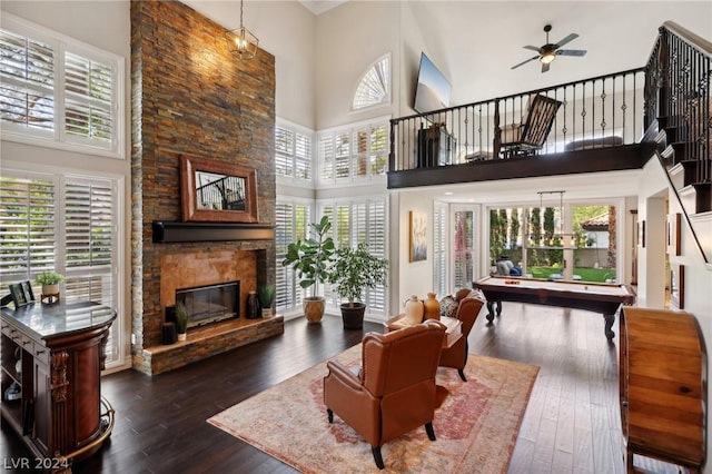 living room featuring a fireplace, a towering ceiling, a healthy amount of sunlight, and dark hardwood / wood-style floors