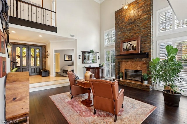 living room featuring a stone fireplace, dark hardwood / wood-style floors, and a high ceiling